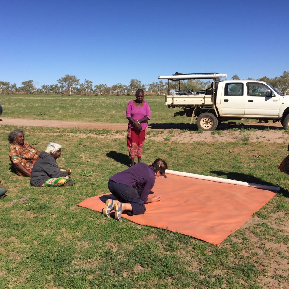 Indigenous women standing around large canvas map