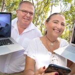 A man and a woman holding two laptops.