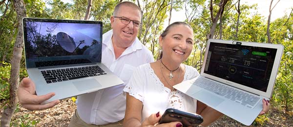 A man and a woman holding two laptops.