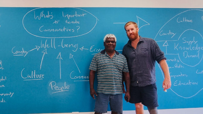Two men standing in front of a blue strategy board